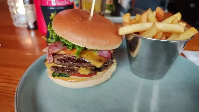 A burger with a steel basket of fries