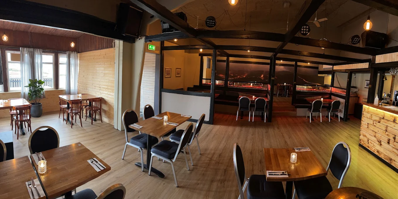 The dining room at Fish House, laid tables under exposed dark beams and pendant bulbs, with booth seating along the far wall